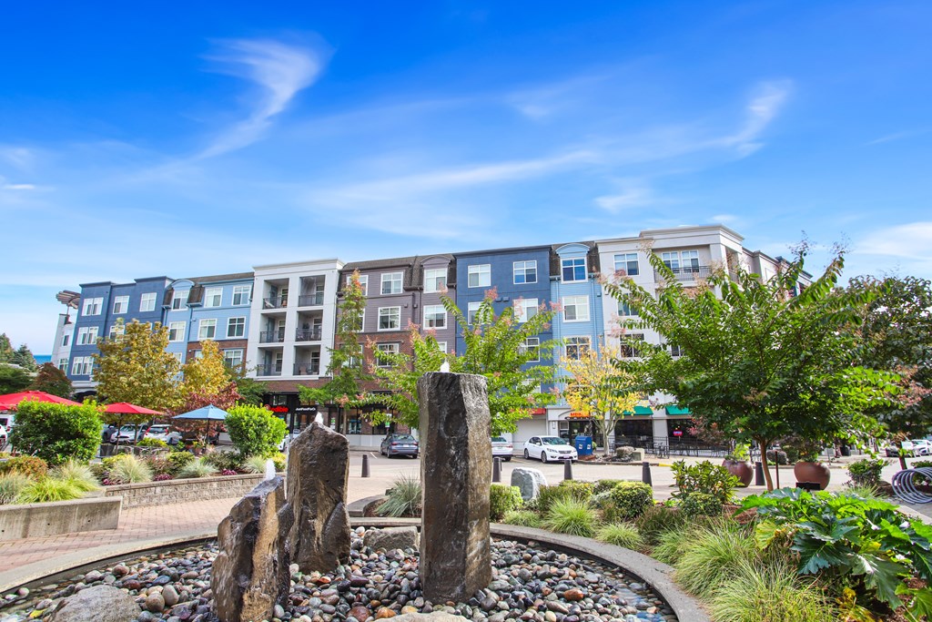 A fountain in the middle of a park with a building in the background.