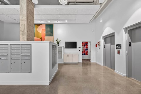 A modern office space with a concrete pillar, a white reception desk, and a red and white abstract painting on the wall.