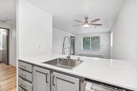 A modern kitchen with a white countertop and a stainless steel sink.