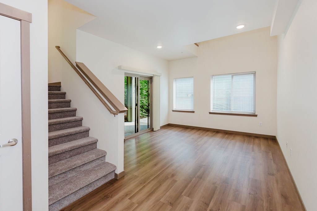 A room with wooden floors and a staircase leading to the upper level.