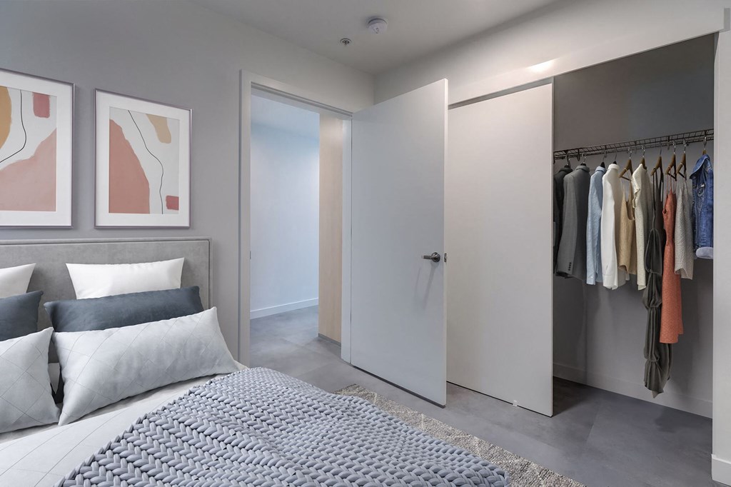 A bedroom with a bed, pillows, a wardrobe, and two framed pictures on the wall.