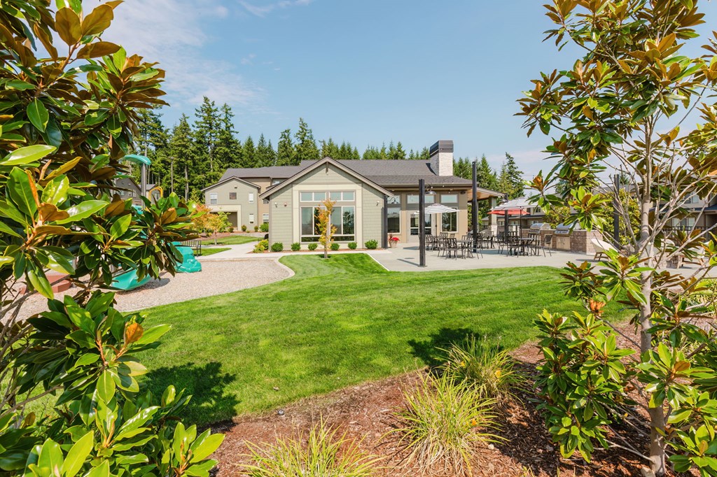 A house with a green lawn and trees in the background.