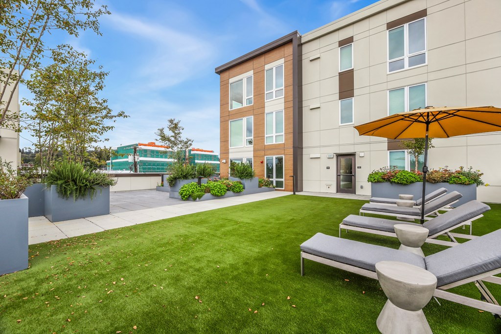 a patio with lawn chairs and umbrellas in front of a building