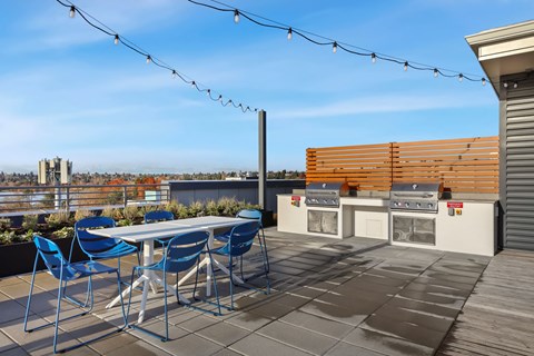 A patio with a table and chairs and a grill.
