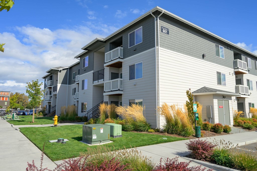 A grey apartment building with a green lawn in front.