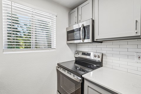 A kitchen with a stove, microwave, and oven.