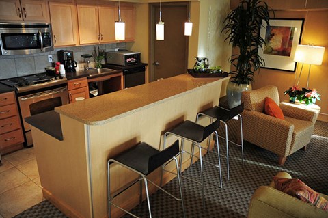 A kitchen with a counter and chairs.