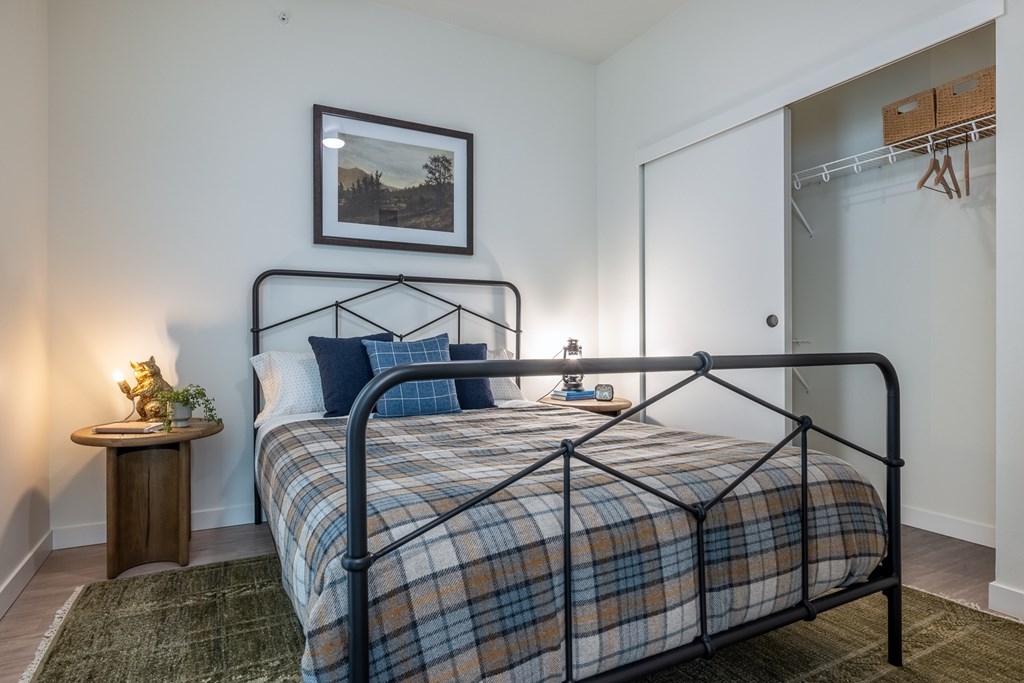 A bedroom with a bed, nightstand, and a painting on the wall.