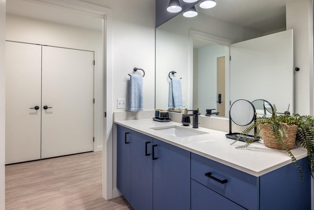A bathroom with a white countertop and blue cabinets.