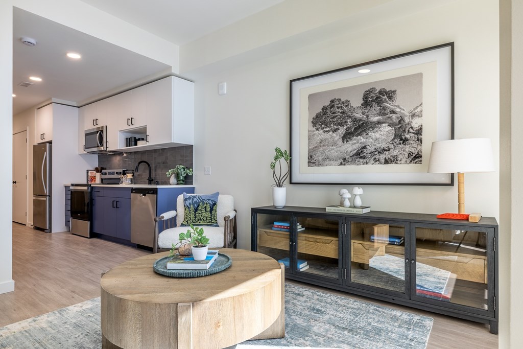 A modern kitchen with a wooden coffee table and a framed black and white picture on the wall.
