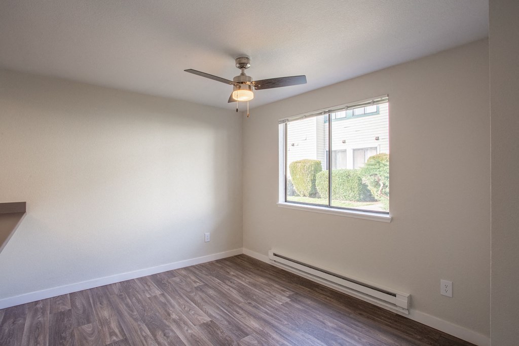 an empty living room with a ceiling fan and a window