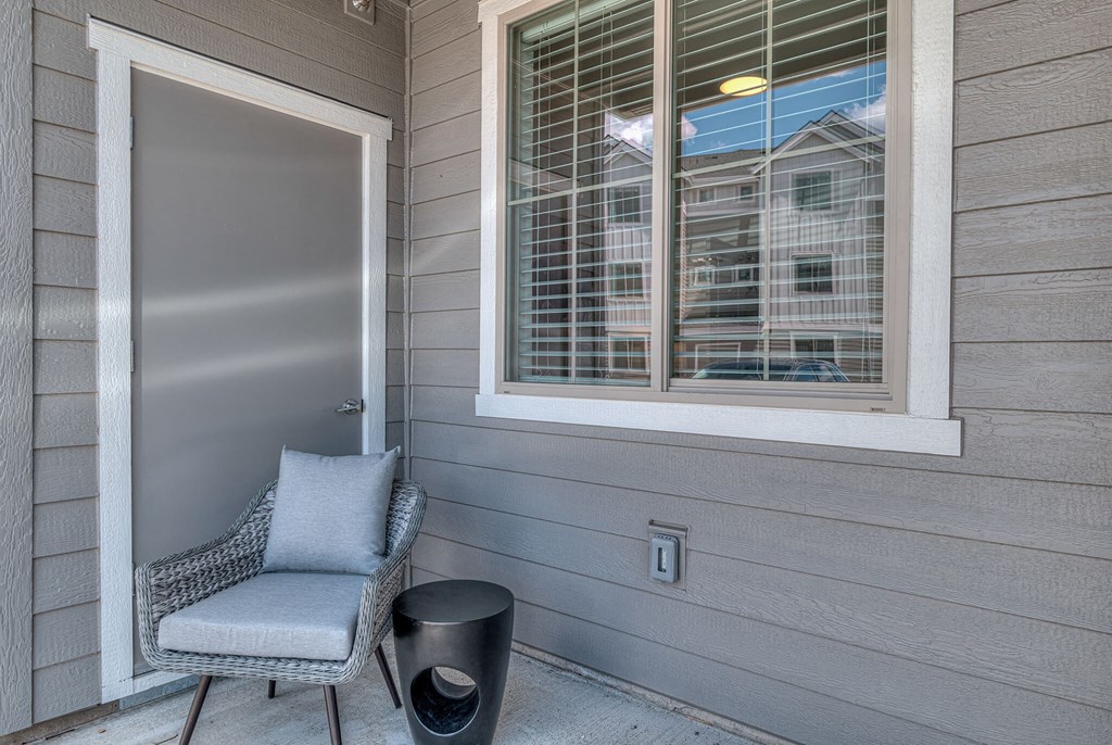 a front porch with a chair and a door with a window