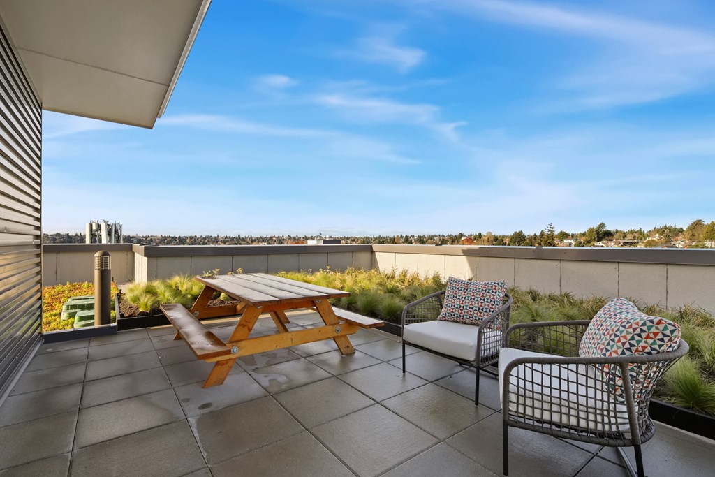 A patio with a table and two chairs overlooking a cityscape.
