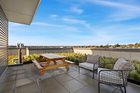 A patio with a table and two chairs overlooking a cityscape.