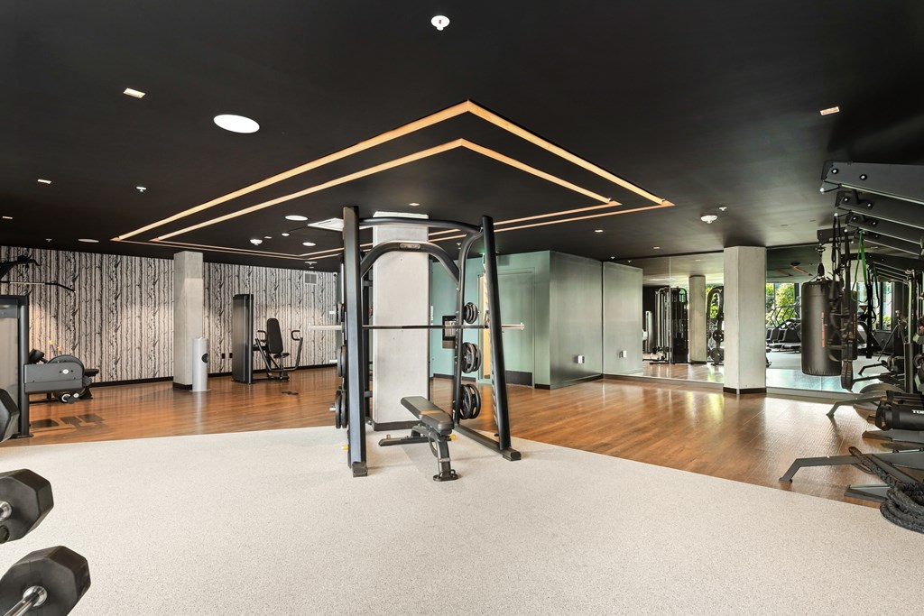 A gym with a variety of equipment including dumbbells, weight machines, and a bench press.