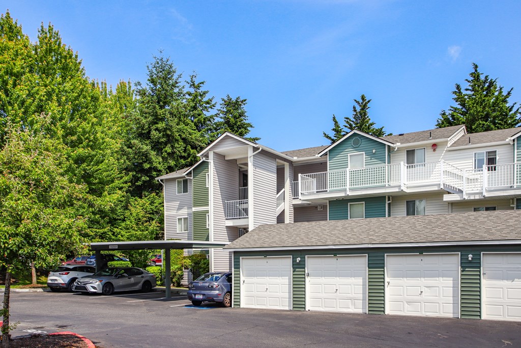 A row of townhouses with garages and cars parked in front.