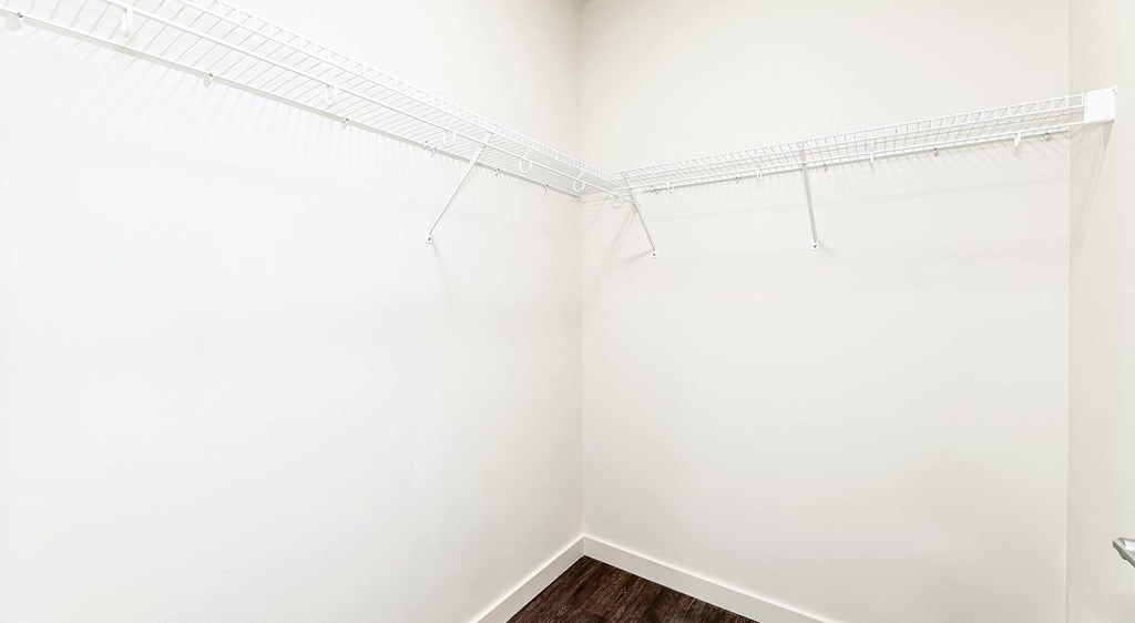 a walk in closet with white walls and