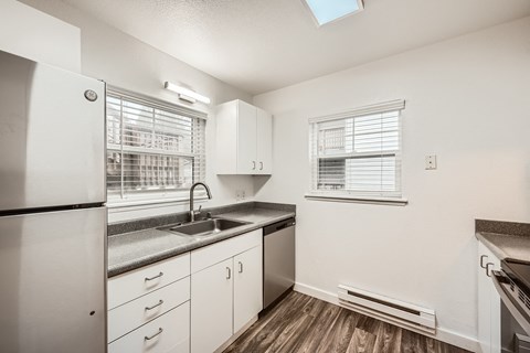 A kitchen with white cabinets and a black fridge.