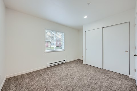 A room with a window, carpet, and a door.