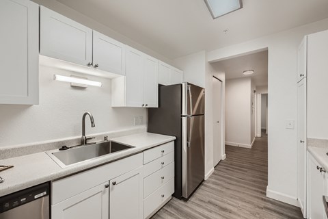 A kitchen with white cabinets and a stainless steel refrigerator.