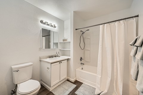 A white bathroom with a toilet, sink, and shower.