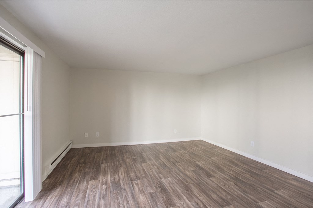 an empty room with wood floors and white walls