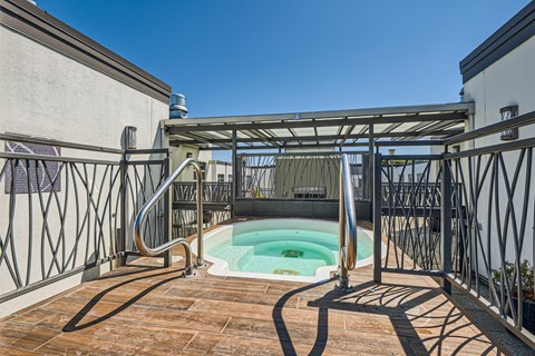a plunge pool sits on the balcony of a house with metal railing