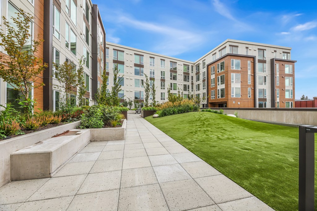 a courtyard with a green lawn and modern apartment buildings