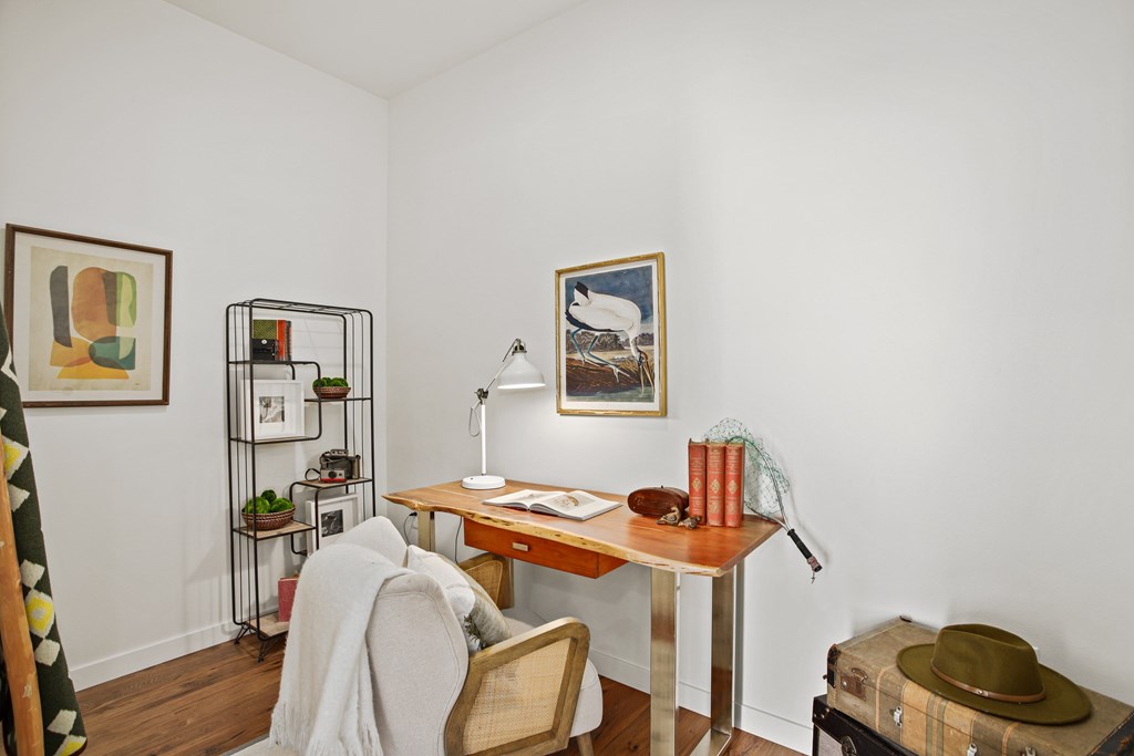 A room with a desk, chair, and a painting on the wall.