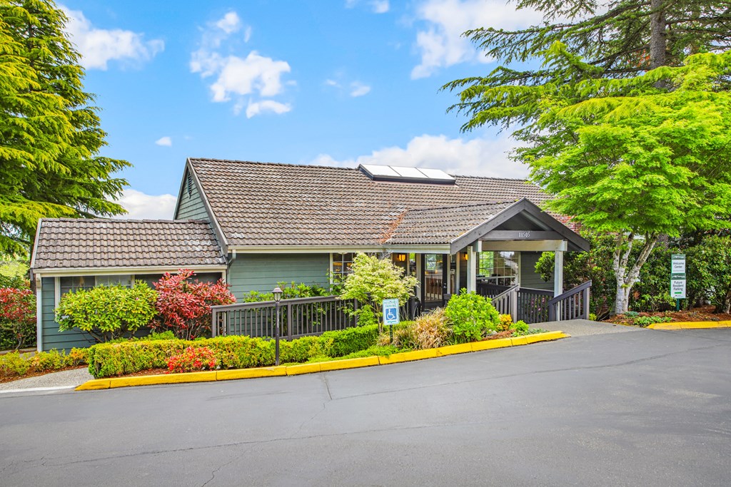 the front of a green house with a porch and a driveway