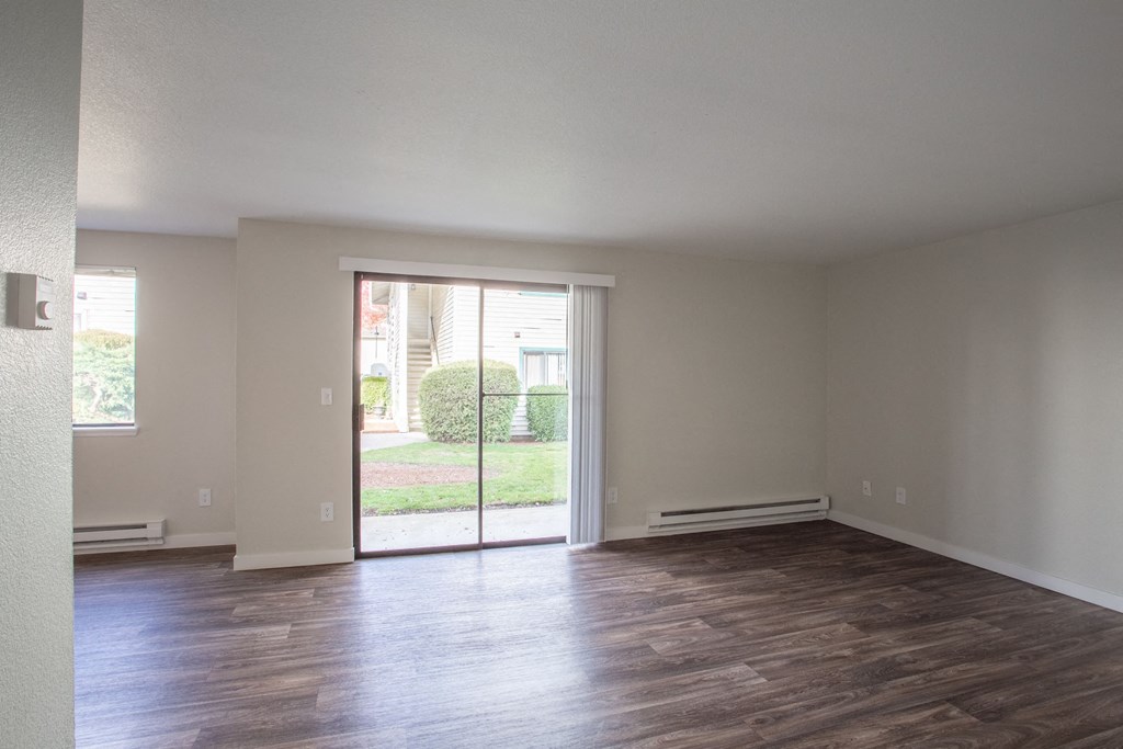 an empty living room with a sliding glass door to a yard