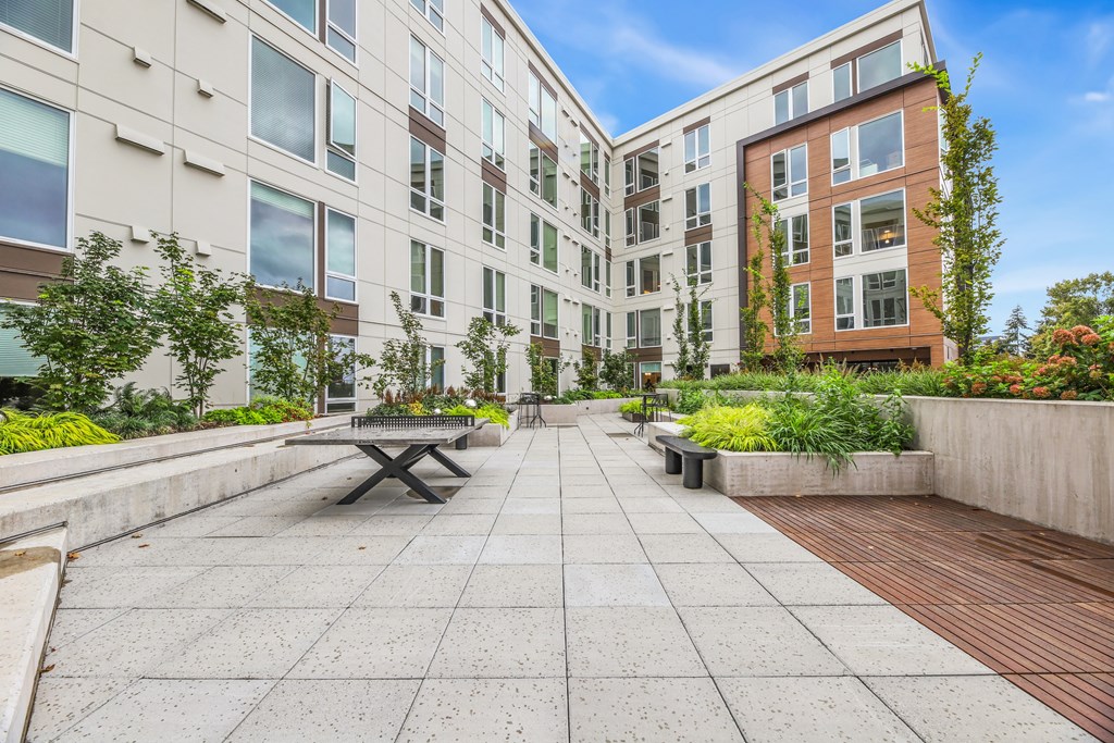 a courtyard with a picnic table and benches in front of an apartment building