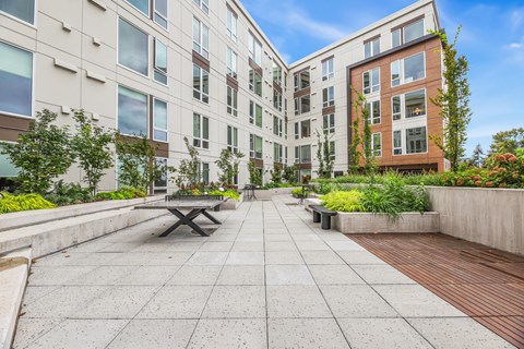 a courtyard with a picnic table and benches in front of an apartment building