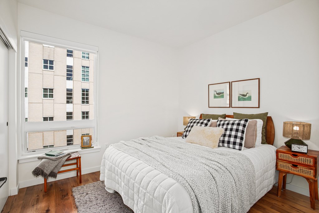 A bedroom with a large bed and a window overlooking a cityscape.