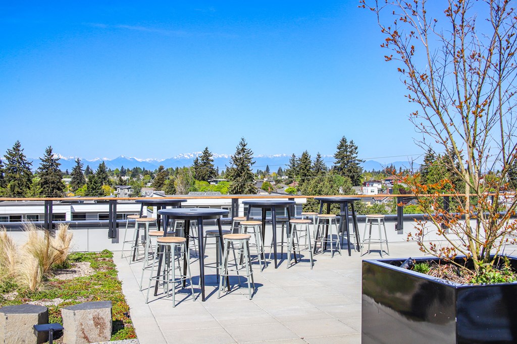an outdoor patio with bar stools and tables overlooking the mountains