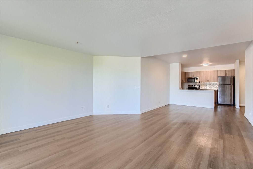 the living room and kitchen of an empty apartment with wood flooring