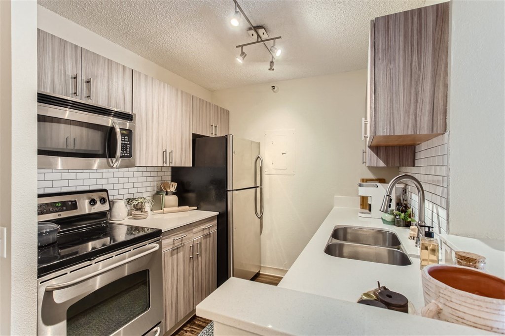 an updated kitchen with stainless steel appliances and white counter tops