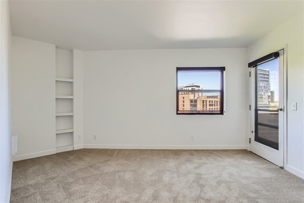 an empty living room with a window and a door to a balcony