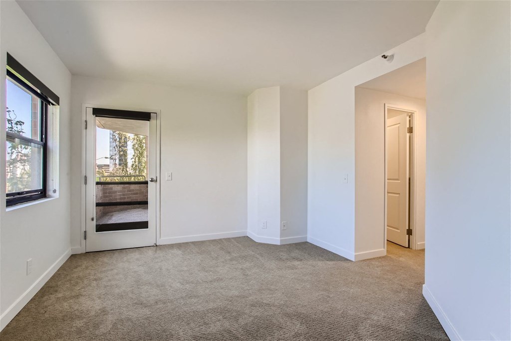 a living room with carpet and a door to a bedroom