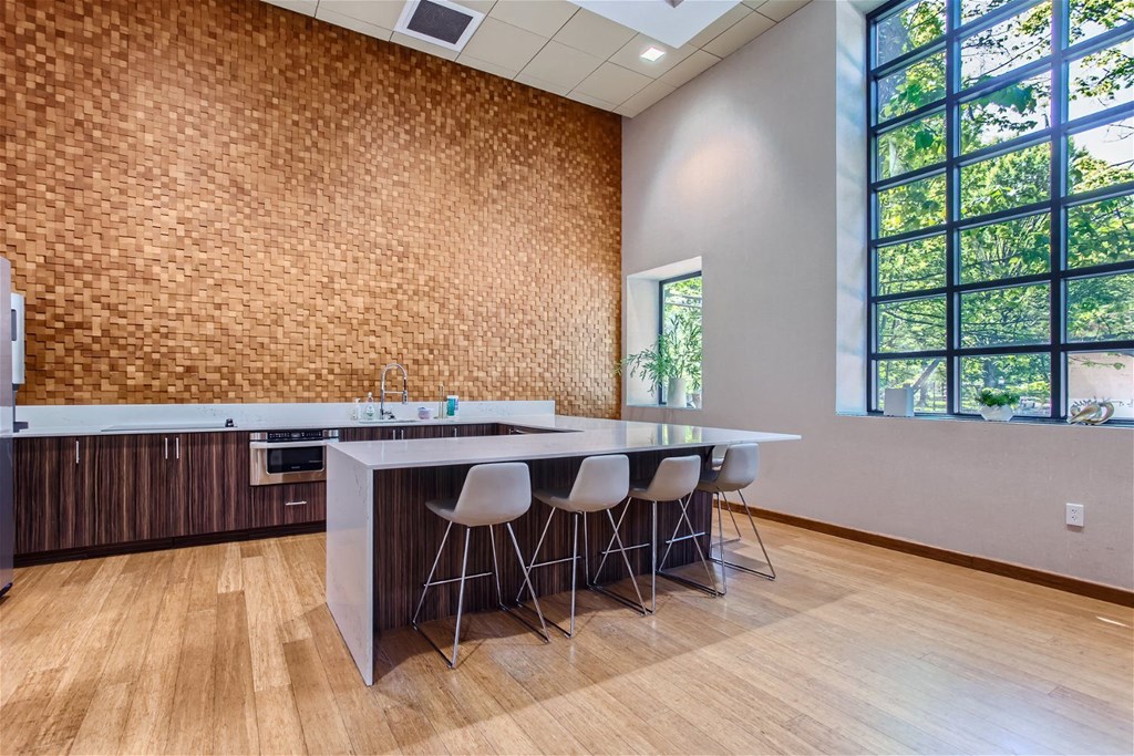 a kitchen with a counter and chairs in front of a window