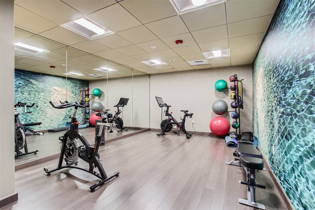 a gym with exercise equipment and a wall with a mural
