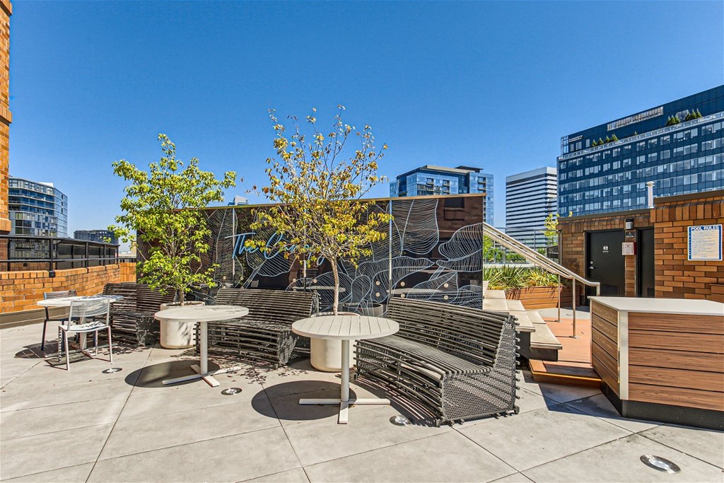 a roof terrace with benches and tables and a building in the background