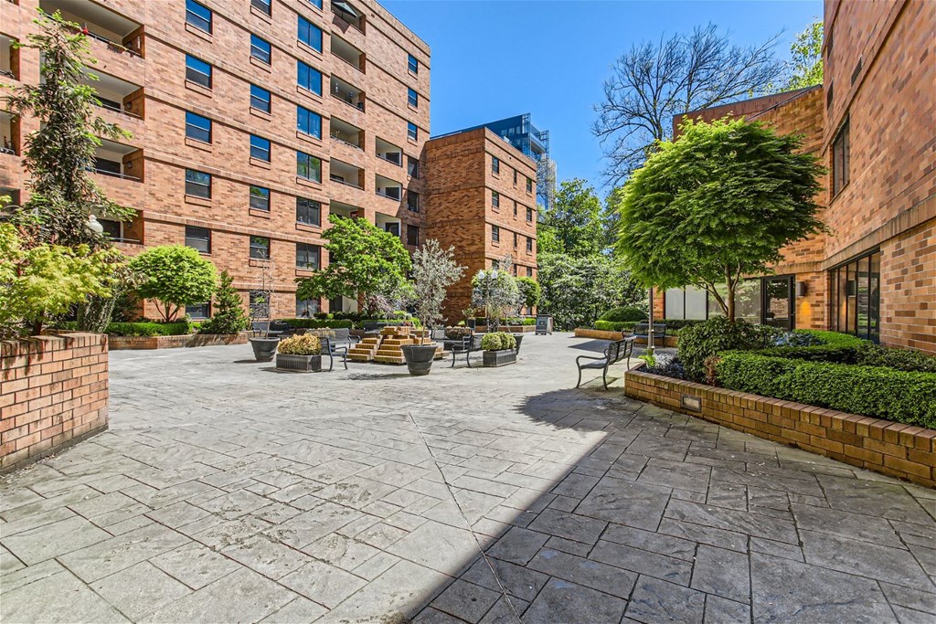 a courtyard between two buildings with benches and trees