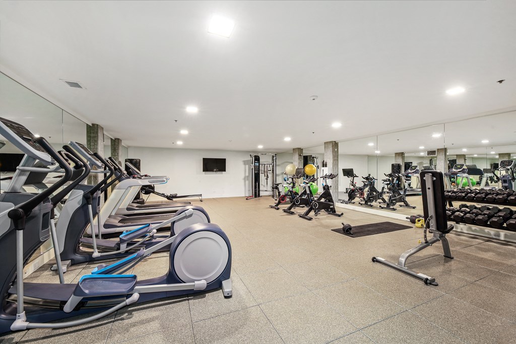 a gym with cardio equipment and weights on a tile floor