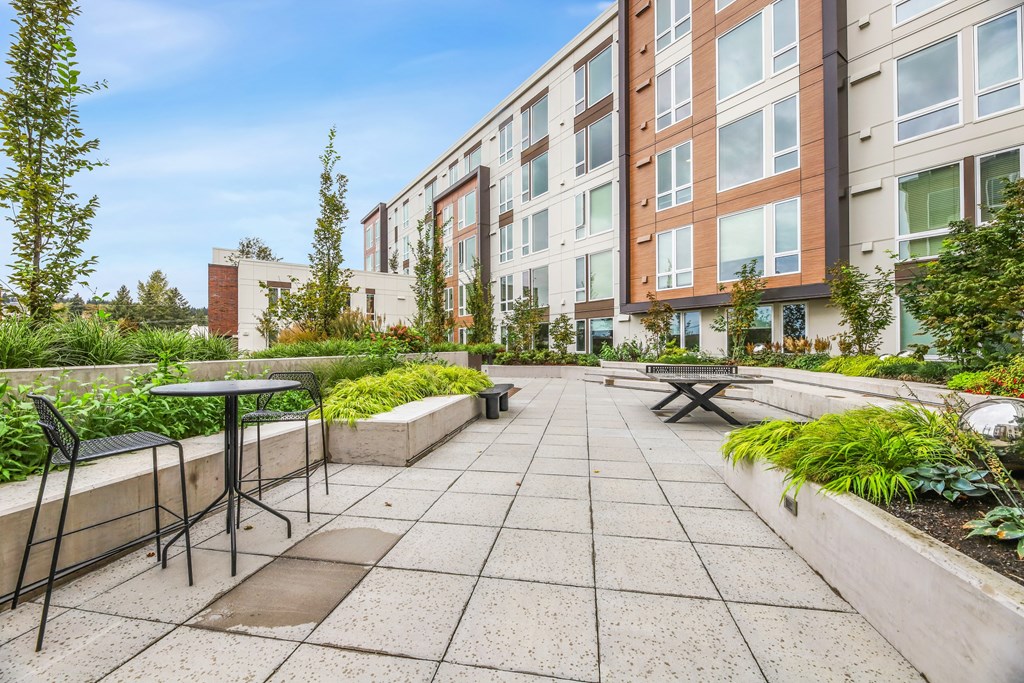 an outdoor patio with a table and chairs in front of an apartment building