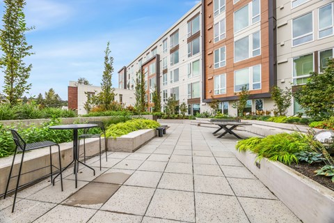 an outdoor patio with a table and chairs in front of an apartment building