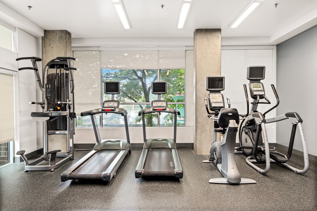 a gym with cardio machines and a large window