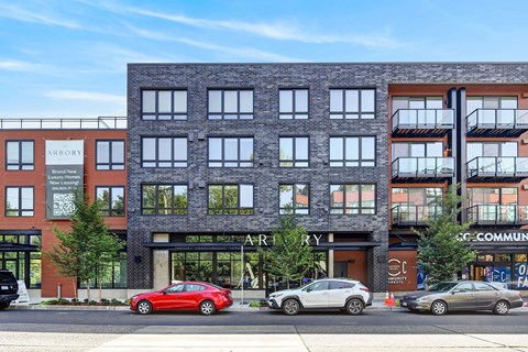 A red car is parked in front of a building with the word "ARBOR" on it.