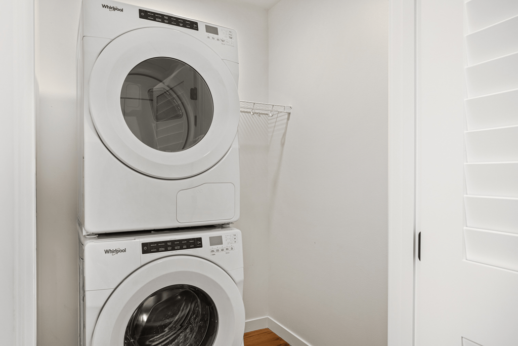 Two white Whirlpool washing machines stacked on top of each other.