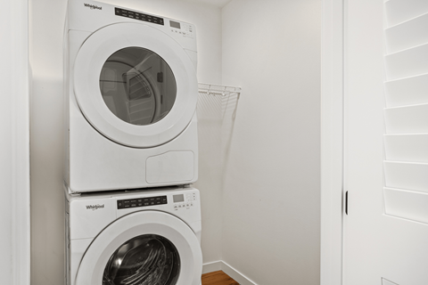 Two white Whirlpool washing machines stacked on top of each other.